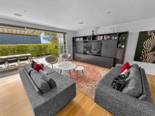 a living room with two couches and a table at Orakei Oasis l Quality 3 Bed House inc Views in Auckland