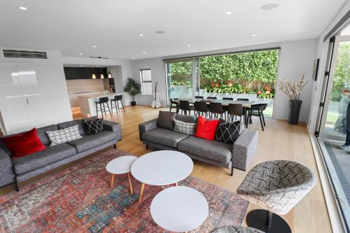 a living room with couches and tables and a kitchen at Orakei Oasis l Quality 3 Bed House inc Views in Auckland