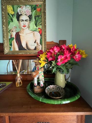 a table with a painting and a vase with flowers at Fridas Accommodation in Raglan