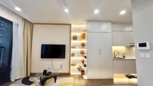 a living room with white cabinets and a tv at Củi Homestay Oasis Ecopark in Kim Quan