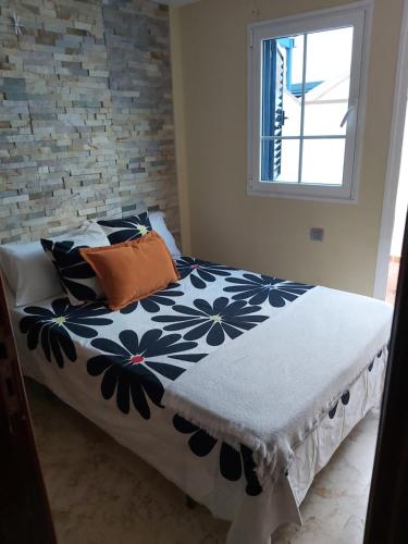 a bed with a black and white comforter and a window at Frataga Home in Playa Honda
