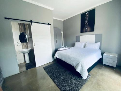 a bedroom with a bed and a bathroom with a sink at Alu Boutique Hotel and Conference in Roodepoort