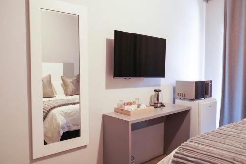 a bedroom with a mirror and a tv on the wall at Alu Boutique Hotel and Conference in Roodepoort