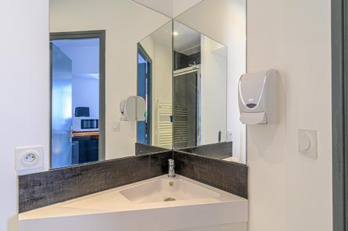 une salle de bain avec un lavabo et un miroir dans l'établissement Studio proche Centre Ville, à Quimper