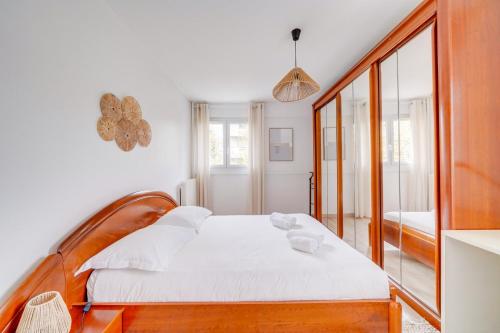 une chambre avec un lit avec des draps blancs et un miroir dans l'établissement Appartement très charmant à Bordeaux avec Parking, à Bordeaux