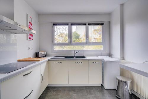 une cuisine blanche avec un évier et une fenêtre dans l'établissement Appartement très charmant à Bordeaux avec Parking, à Bordeaux