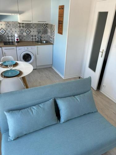 un canapé bleu dans une cuisine avec une table dans l'établissement Studio proche plage et commerces, à Les Sables-dʼOlonne
