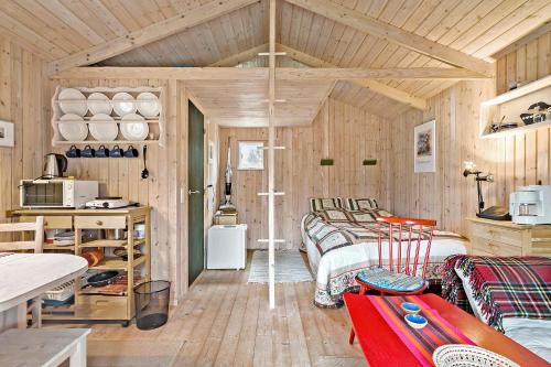 a room with two beds and a kitchen with wooden walls at Charmerende skovhytte in Ringkøbing