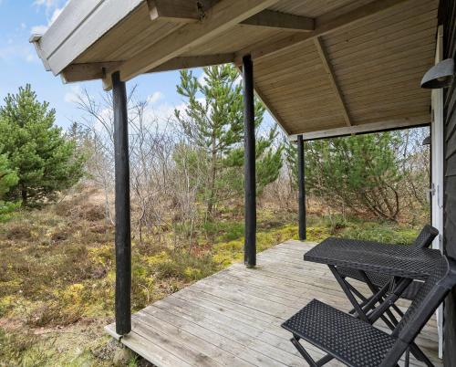 a porch with a chair and a table on a wooden deck at Charmerende skovhytte in Ringkøbing