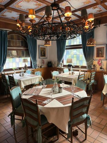 a dining room with tables and chairs and a chandelier at Landhotel Traube in Baden-Baden