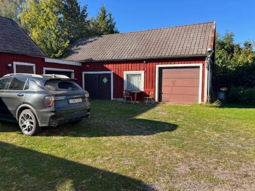 a car parked in front of a red house at Villa Madame in Väderstad