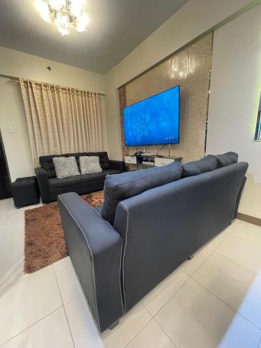 a living room with a couch and a flat screen tv at Two Bedroom with Balcony 70sqm -Pasig in Manila