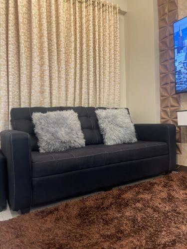 a black couch with two pillows on it in a living room at Two Bedroom with Balcony 70sqm -Pasig in Manila