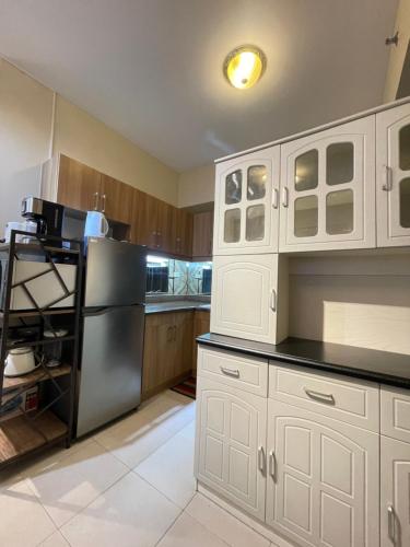 a kitchen with white cabinets and a black refrigerator at Two Bedroom with Balcony 70sqm -Pasig in Manila