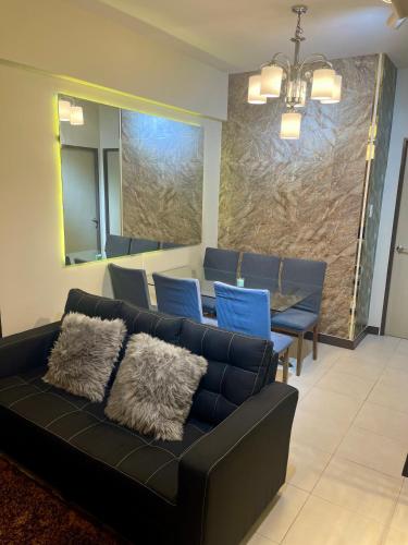 a living room with a black couch and a table at Two Bedroom with Balcony 70sqm -Pasig in Manila