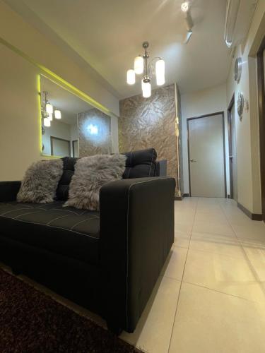 a black couch in a living room with a mirror at Two Bedroom with Balcony 70sqm -Pasig in Manila