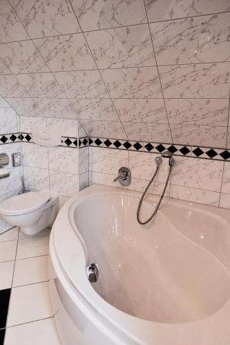 a white bath tub in a bathroom with a toilet at Landhotel Traube in Baden-Baden