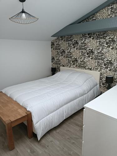 une chambre avec un lit blanc et un mur de briques dans l'établissement La Rochette - Appartement, à Les Clouzeaux