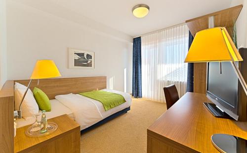 a bedroom with a bed and a desk with a television at Sapia Hotel St. Fridolin in Bad Säckingen