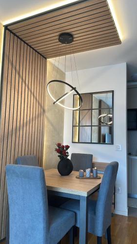 a dining room table with blue chairs and a light fixture at Lux Apartmani Park Novi in Novi Sad