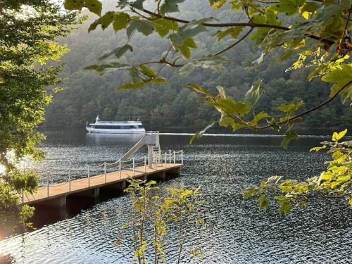 a boat on a lake with a bridge and a boat at Urlaub in der Eifel direkt am Rursee - Seewinkel in Simmerath