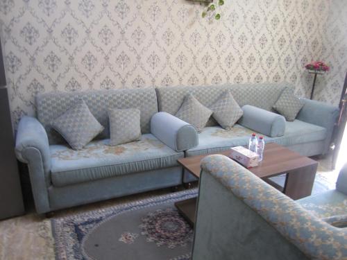 a living room with a blue couch and a table at العين الهيلي مصباح بيت 11 in Al Ain