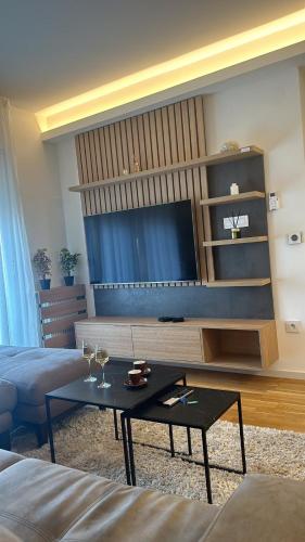 a living room with a table and a tv at Lux Apartmani Park Novi in Novi Sad