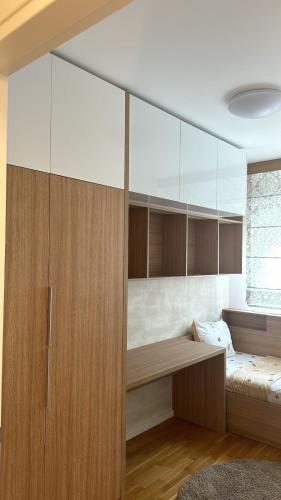 a bedroom with a bed and a large wooden cabinet at Lux Apartmani Park Novi in Novi Sad