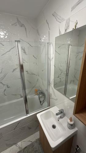 a white bathroom with a sink and a shower at Lux Apartmani Park Novi in Novi Sad