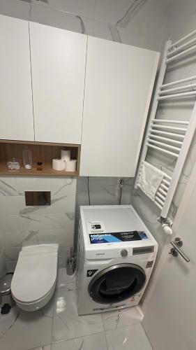 a bathroom with a toilet and a washer and dryer at Lux Apartmani Park Novi in Novi Sad