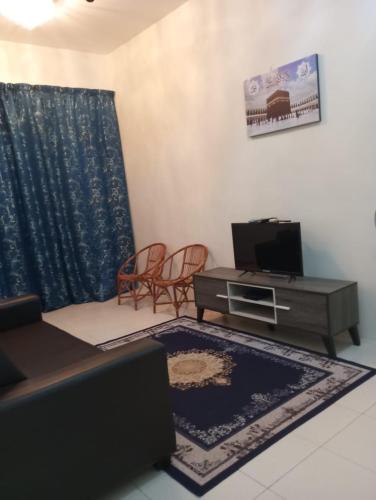 a living room with a couch and a tv at Lily Impiana Homestay in Baling