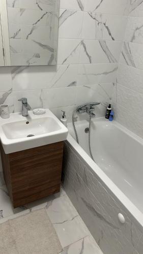 a white bathroom with a sink and a bath tub at Lux Apartmani Park Novi in Novi Sad