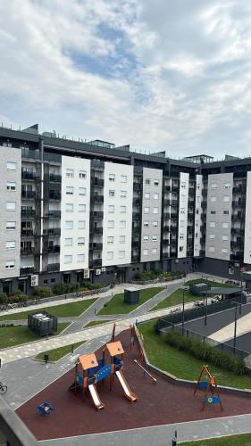 an empty playground in front of a large building at Lux Apartmani Park Novi in Novi Sad