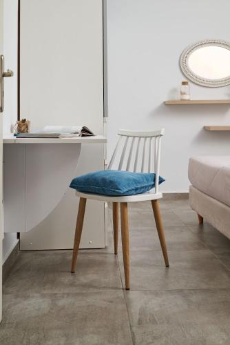 a white chair with a blue seat sitting next to a desk at Votsalo in Ierápetra