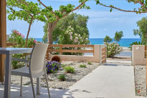 a patio with a table and a bench and the ocean at Votsalo in Ierápetra