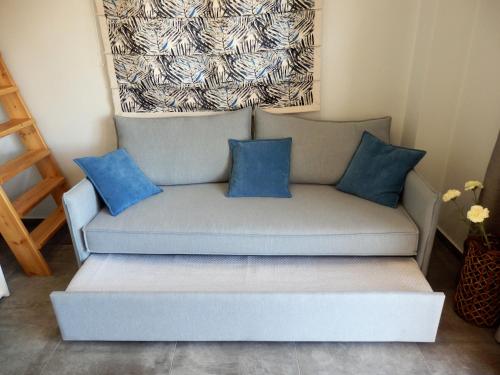 a couch with blue pillows in a room at Votsalo in Ierápetra