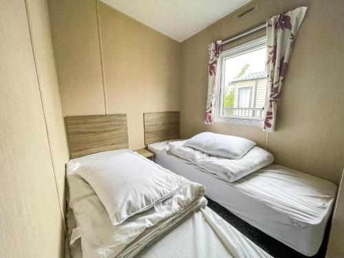 two beds in a small room with a window at Wonderful 6 Berth Caravan With Decking & River Views At Heacham Beach Ref 21003A in Heacham