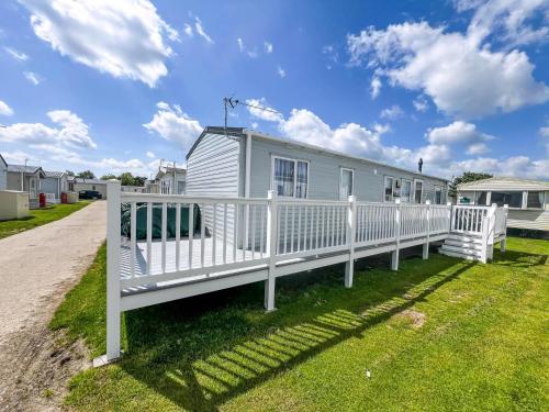 a mobile home with a white fence at Stunning10 Berth Caravan With Decking At Broadland Sands In Suffolk Ref 20082Bs in Hopton on Sea