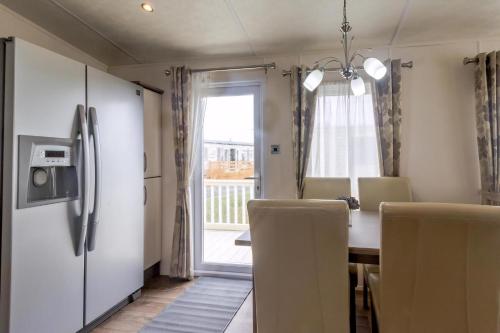 a kitchen with a table and chairs and a refrigerator at Beautiful 6 Berth Caravan By The Beach In Suffolk Ref 40076Nd in Lowestoft