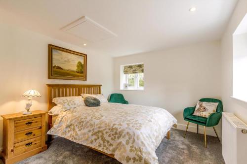 una camera da letto con un letto e due sedie verdi di Cottage In Norfolk Sleeps 23 - Private Pool, Fishing Lake, Hot Tub Ref 99008Sc a Hockham