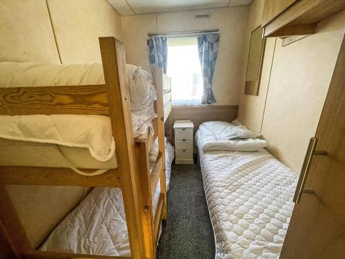 une petite chambre avec deux lits superposés et une fenêtre dans l'établissement Brilliant 8 Berth Caravan At Valley Farm Holiday Park, Essex Ref 46443V, à Great Clacton