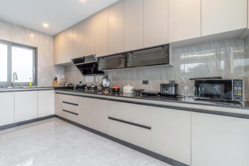 a kitchen with white cabinets and a microwave at T M L-Manor House 6 bedroom-independent swimming pool and powerful KTV in Ban Huai Yai