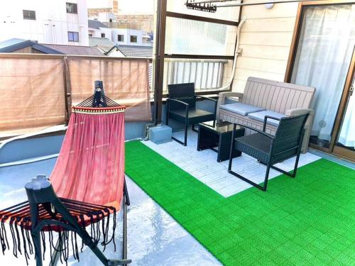 a patio with a hammock and chairs on a balcony at KENKOU Room -健康ルーム 大阪- in Osaka