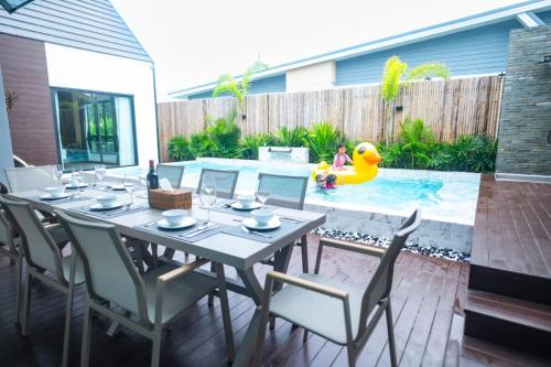 eine Terrasse mit Tisch und Stühlen und einem Pool in der Unterkunft Thebeyonder house Pattaya, Pet friendly in Ban Huai Yai