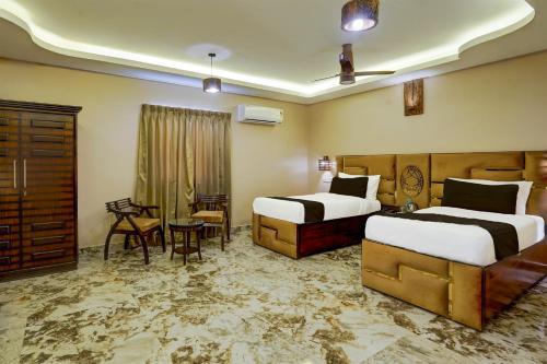 a hotel room with two beds and a table and chairs at Super Townhouse NK Vivanta Luxury Rooms in Chennai