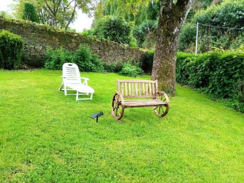 a bench and two chairs sitting in a yard at Chambre d'hôte à coté de la voie verte in Gourin