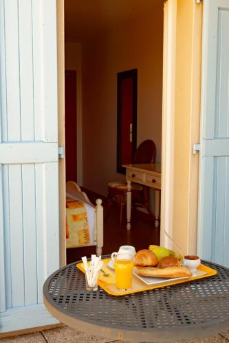 a table with a tray of bread and orange juice at Logis Hotels - Le relais des deux vallées - Hôtel et restaurant in Salvagnac