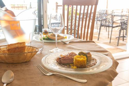 a table with a plate of food and wine glasses at Logis Hotels - Le relais des deux vallées - Hôtel et restaurant in Salvagnac