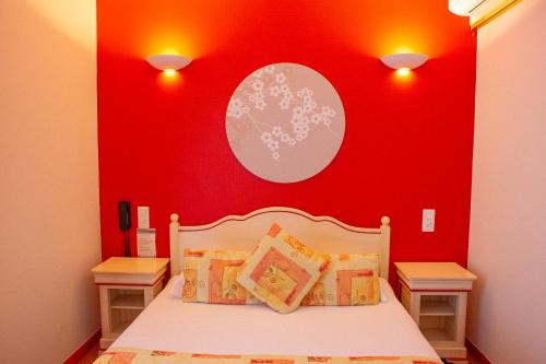 a bedroom with a bed with a red wall at Logis Hotels - Le relais des deux vallées - Hôtel et restaurant in Salvagnac