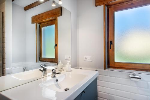 a white bathroom with a sink and a mirror at Casa 8plazas, 7km de la playa La Franca, Asturias in Boquerizo